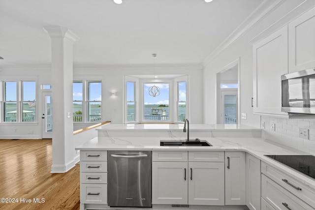 kitchen featuring light stone counters, white cabinets, appliances with stainless steel finishes, and crown molding