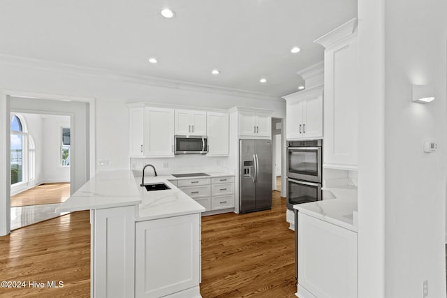 kitchen featuring white cabinets, stainless steel appliances, sink, kitchen peninsula, and crown molding