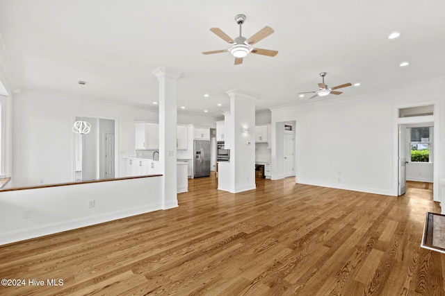 unfurnished living room with ceiling fan, light hardwood / wood-style flooring, ornamental molding, and ornate columns