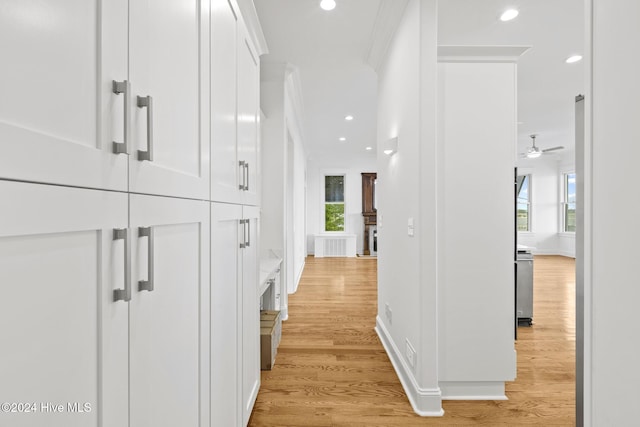 hallway featuring light wood-type flooring, a wealth of natural light, and crown molding