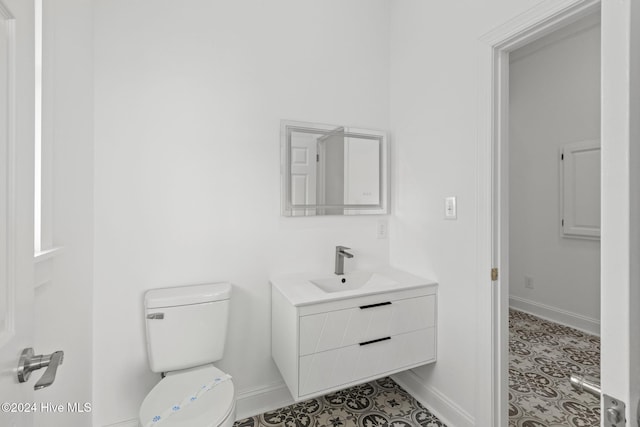 bathroom with toilet, vanity, and tile patterned flooring