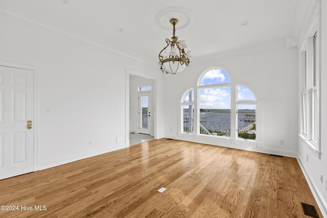 unfurnished living room featuring light hardwood / wood-style floors, ornamental molding, and a chandelier