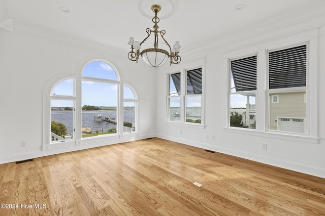 unfurnished dining area featuring light wood-type flooring, an inviting chandelier, ornamental molding, and a water view