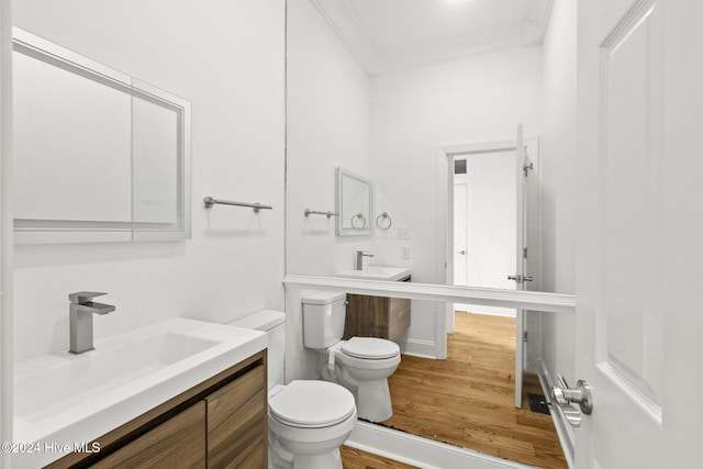 bathroom with toilet, crown molding, wood-type flooring, and vanity