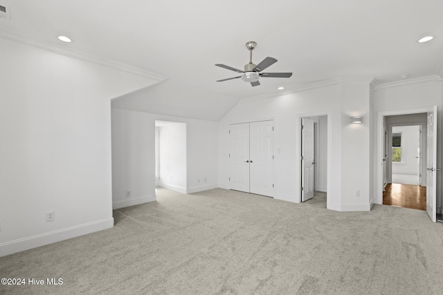 unfurnished bedroom featuring lofted ceiling, ceiling fan, crown molding, and light colored carpet