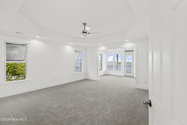 carpeted spare room with ceiling fan, crown molding, and a raised ceiling