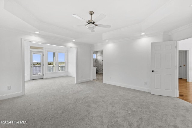 carpeted spare room with a raised ceiling, ceiling fan, and crown molding