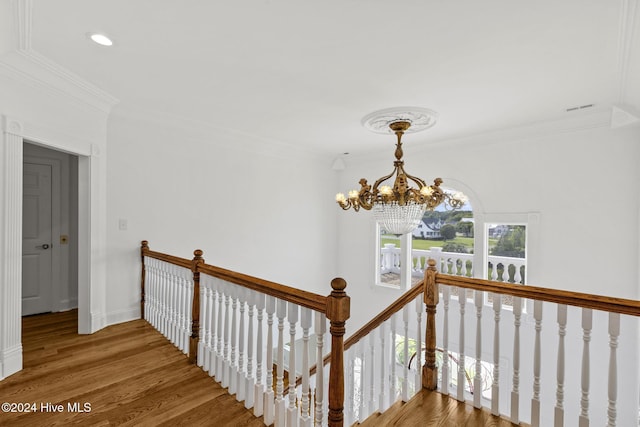 hallway featuring an inviting chandelier, ornamental molding, and hardwood / wood-style flooring