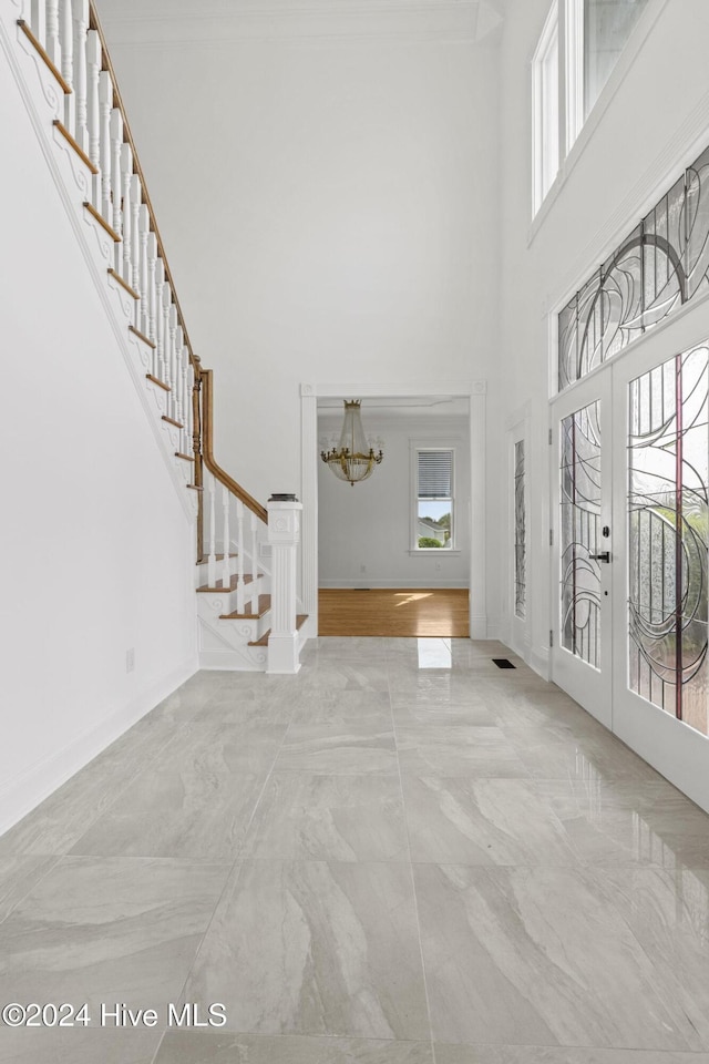 entrance foyer with a high ceiling, french doors, and a notable chandelier