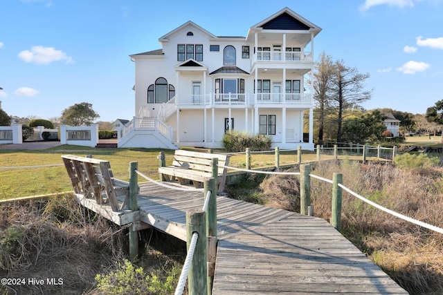 back of property with a balcony and a lawn