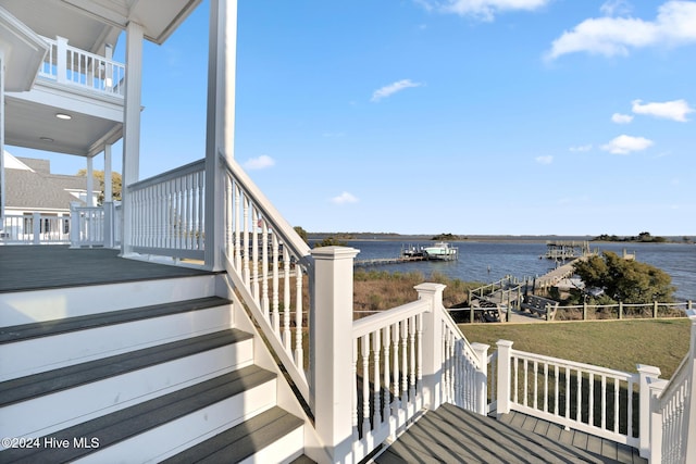 deck with a water view, a dock, and a lawn