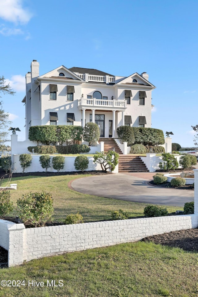 exterior space featuring a balcony and a front lawn