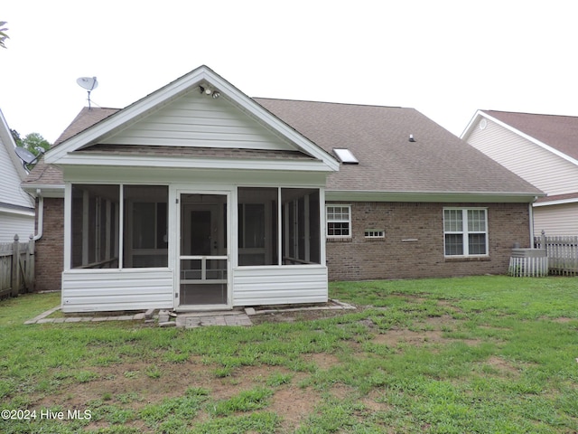 rear view of house featuring a sunroom and a yard