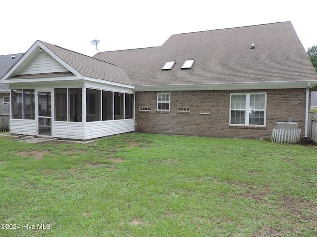 rear view of house with a lawn and a sunroom