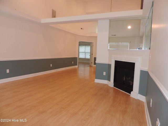 unfurnished living room featuring a towering ceiling and light hardwood / wood-style flooring