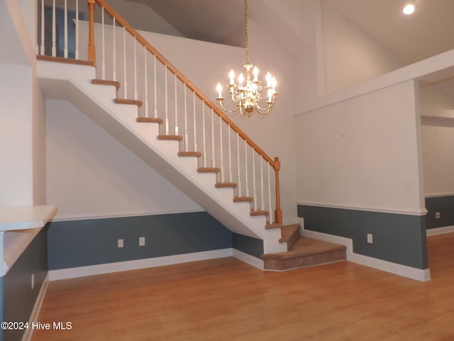 staircase featuring hardwood / wood-style flooring, a notable chandelier, and a towering ceiling