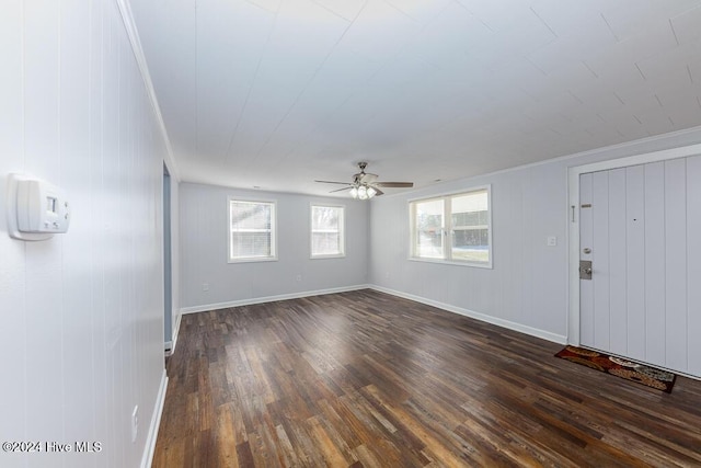 spare room featuring dark hardwood / wood-style flooring, ceiling fan, ornamental molding, and wood walls