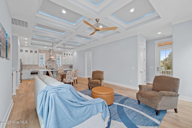 unfurnished living room featuring a large fireplace, a healthy amount of sunlight, light wood-type flooring, and coffered ceiling