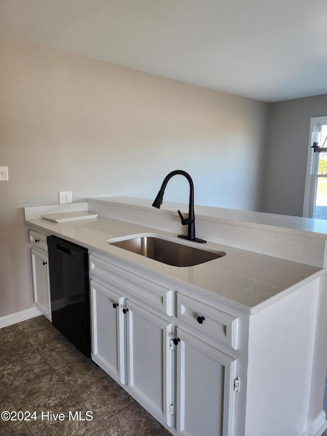 kitchen featuring kitchen peninsula, light stone countertops, sink, white cabinets, and black dishwasher