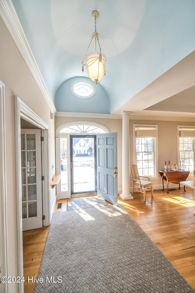 foyer entrance with lofted ceiling, crown molding, light wood-type flooring, and ornate columns