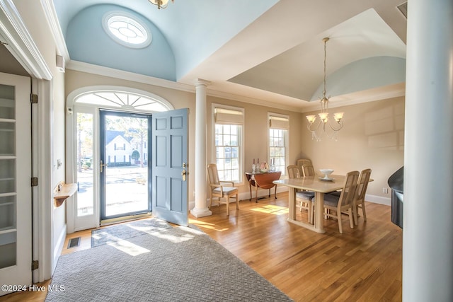 entryway with a chandelier, vaulted ceiling, light hardwood / wood-style flooring, and ornate columns