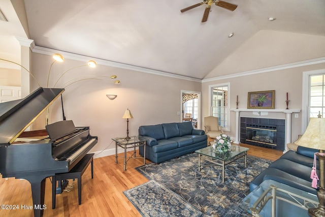 living room with crown molding, a fireplace, vaulted ceiling, and light wood-type flooring