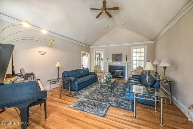 living room with a tiled fireplace, crown molding, and hardwood / wood-style flooring