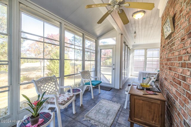 sunroom featuring vaulted ceiling with beams, plenty of natural light, ceiling fan, and wooden ceiling