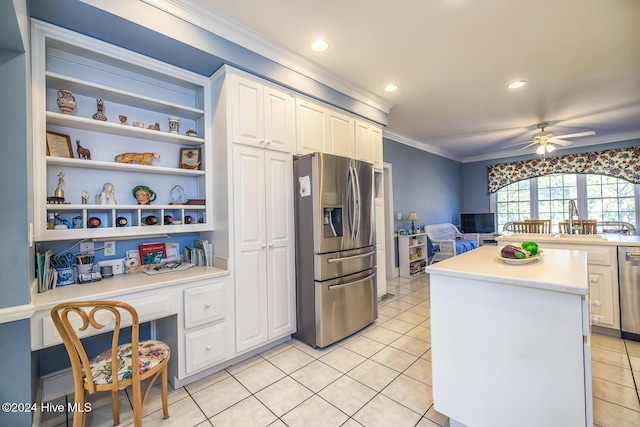 kitchen with a kitchen island, appliances with stainless steel finishes, built in desk, white cabinets, and crown molding