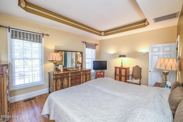 bedroom with a tray ceiling and light hardwood / wood-style floors