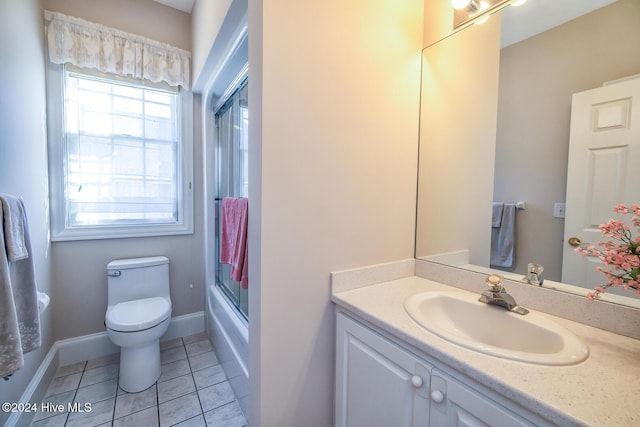 full bathroom with bath / shower combo with glass door, vanity, tile patterned floors, and toilet