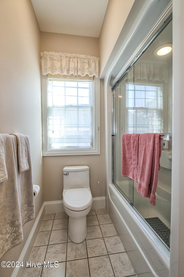 bathroom with combined bath / shower with glass door, tile patterned floors, and toilet