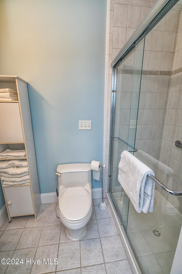 bathroom with tile patterned flooring, an enclosed shower, and toilet