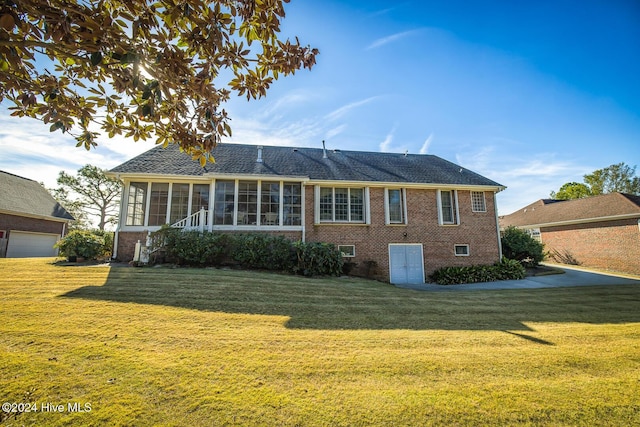 rear view of property featuring a yard and a sunroom