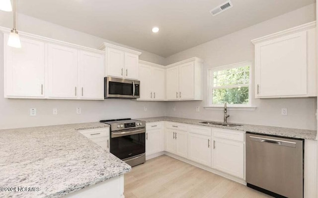 kitchen with sink, white cabinets, hanging light fixtures, and appliances with stainless steel finishes