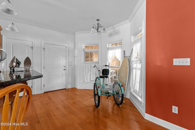 foyer with light wood-type flooring, crown molding, and an inviting chandelier