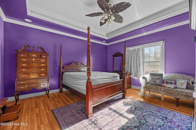 bedroom featuring hardwood / wood-style floors, ceiling fan, a raised ceiling, and crown molding