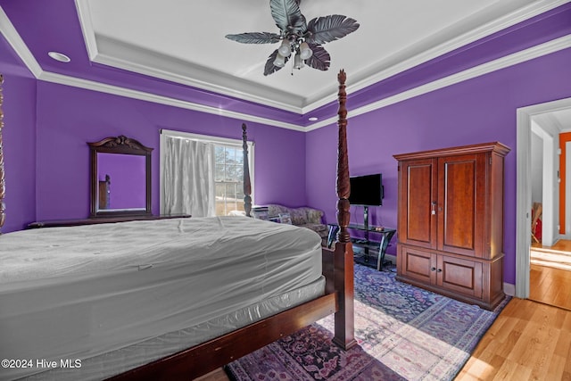 bedroom featuring ceiling fan, ornamental molding, a tray ceiling, and light hardwood / wood-style flooring