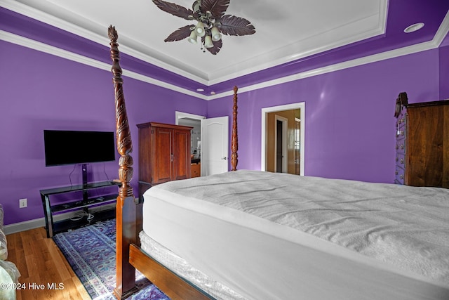 bedroom featuring hardwood / wood-style floors, a tray ceiling, ceiling fan, and crown molding