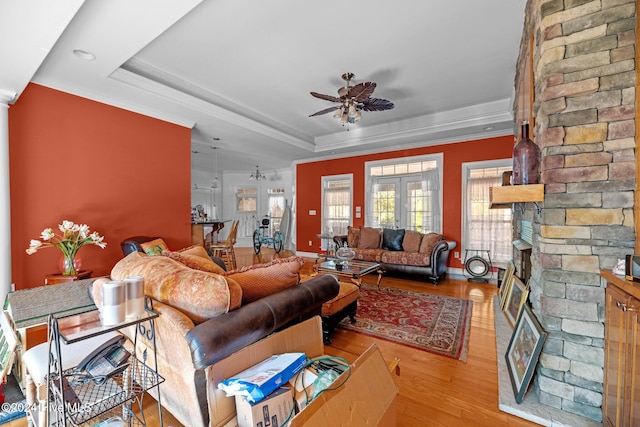 living room featuring french doors, light hardwood / wood-style floors, ceiling fan, and a tray ceiling