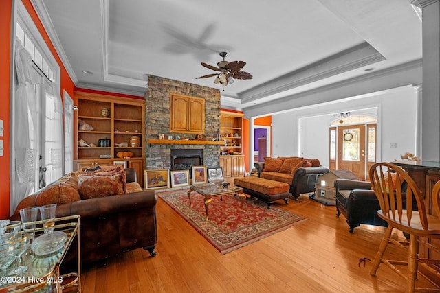 living room featuring built in shelves, a raised ceiling, and wood-type flooring