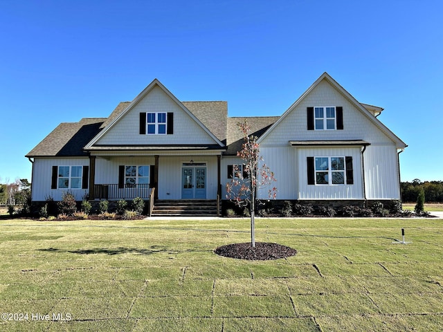 view of front facade featuring french doors, covered porch, and a front yard