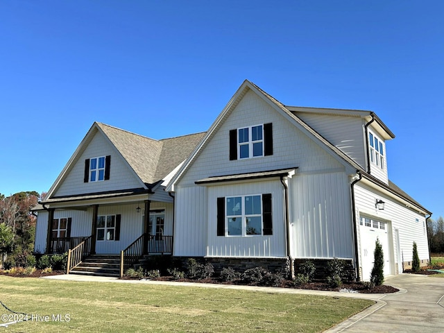 view of front of home featuring a front yard, a porch, and a garage