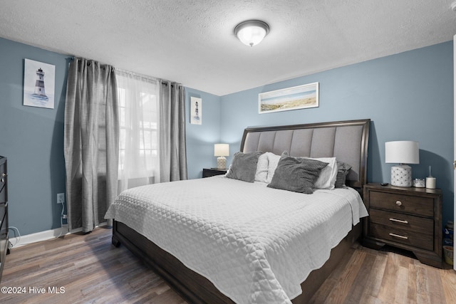 bedroom with dark hardwood / wood-style flooring and a textured ceiling