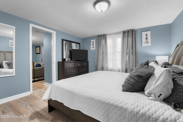 bedroom with a textured ceiling and light wood-type flooring