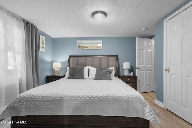 bedroom with light hardwood / wood-style flooring and a textured ceiling