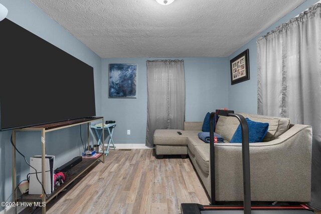 living room with a textured ceiling and light wood-type flooring