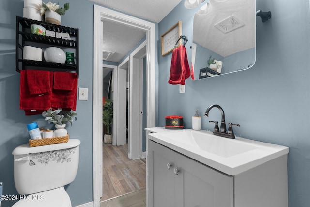 bathroom with hardwood / wood-style floors, vanity, a textured ceiling, and toilet