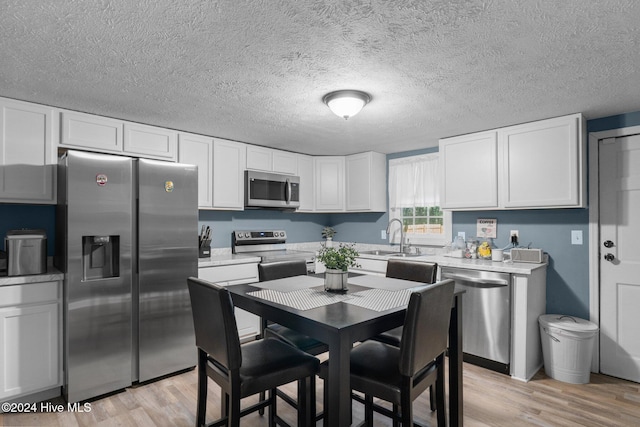 kitchen featuring sink, white cabinets, stainless steel appliances, and light hardwood / wood-style floors