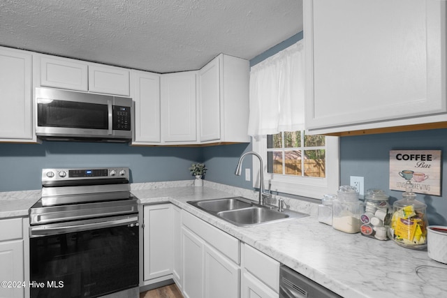 kitchen featuring white cabinets, a textured ceiling, stainless steel appliances, and sink